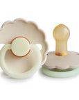 Two Frigg Daisy Night Rubber baby pacifiers in Cream and Croissant on a white background
