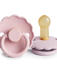 Two Frigg Daisy baby pacifiers in Baby Pink and Soft Lilac with a white background