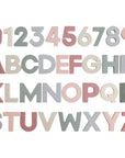 The mushie Letters & Numbers Bath Play Set features numbers 0-9 and A-Z in soft pastel pink, gray, and beige. Arranged on a white background, these foam pieces are perfect bath toys with educational benefits.