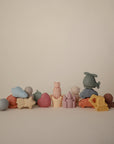 The mushie Sealife Mold Free Bath Play Set features pastel-colored silicone toys in fun shapes, including stars, animals, a helicopter, and a truck, neatly arranged against a simple light background.