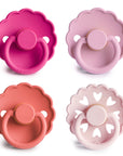 The FRIGG Natural Rubber Pacifier 4-Pack by FRIGG features four classic Danish pacifiers in pink and rose shades, each with a scalloped edge or heart-shaped cutout, arranged in a square on a white background. Made from natural rubber.