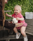 Toddler on bench reaches for teapot beside a mushie Diaper Caddy.
