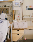 Lifestyle image in a hospital room with medical equipment and a Fog Diaper Caddy on the side table.