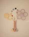 The mushie Silicone Pacifier Clip | Hera features pastel, food-grade silicone teethers in shapes like a flower, palette, and sun hanging from three beaded pacifier clips, all with a soft minimalist design on a neutral background.