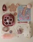Collection of pink children's tableware and toys on a white surface