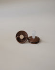 Two FRIGG Little Viking Silicone pacifiers by FRIGG, made in Denmark from medical grade silicone, rest on a plain light background—one on its side showing the nipple, the other facing up to display the base.