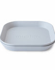 A stack of mushie Square Dinnerware Plates in light gray, featuring "mushie" embossed on the top plate. Made from BPA-free plastic, this baby plate set is shown against a white background.