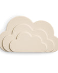 Four mushie Cloud Teether silicone teethers in cream, shaped like clouds and in different sizes, are stacked overlapping on a white background.