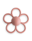 The mushie Daisy Rattle Teether is a pink, flower-shaped baby toy with six textured petals, a smooth round center embossed with "mushie," and a charming daisy design—perfect for teething.