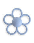 The mushie Daisy Rattle Teether is a light blue, flower-shaped baby teether with six textured silicone petal loops and a smooth center, designed for soothing comfort.