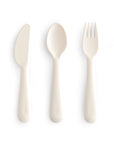 Three white plastic utensils—a knife, spoon, and fork—from the mushie Dinnerware Cutlery Set are displayed side by side on a plain white background, highlighting this non-toxic cutlery set.