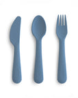 The mushie Dinnerware Cutlery Set features a blue, non-toxic silicone knife, spoon, and fork arranged side by side on a white background.