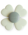 The mushie Suction Spinner Toy, in the Lucky colorway, features a flower shape with four white heart-shaped petals and a gray center embossed with "mushie," made from food-grade silicone for a delightful sensory experience.