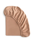 The mushie Stretchy MINI Crib Sheet in tan/caramel, made from breathable organic cotton, is shown on a white background with elasticated edges and detailed corners prominently featured.
