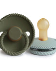 The Mushie FRIGG Rope Natural Rubber Pacifier 2-Pack features two baby essentials with round, rope-textured bases—one upright in olive green, the other light blue on its side—both with natural rubber latex nipples for comfort.