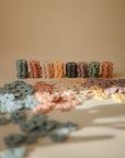 Rows of pastel HEX Connect tokens by mushie, flower-shaped and scattered on a neutral surface—an inviting STEM building toy set that encourages spatial reasoning, displayed under soft lighting.