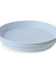 The mushie Round Dinnerware Plate is light blue silicone with slightly raised edges and 'mushie' embossed in the center. This minimalist, non-toxic plate is dishwasher safe—ideal for those seeking a safe, stylish dining option.