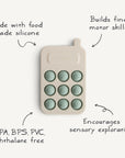 The mushie Phone Press Toy is a beige, food-grade silicone toy with nine green buttons. BPA/BPS/PVC/phthalate free, it helps build fine motor skills and encourages sensory exploration for little hands.