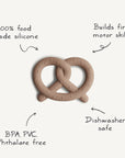 The mushie Pretzel Teether, made from 100% food-grade silicone, is shown on a white background. Features include BPA, PVC & phthalate-free material, dishwasher safety, non-toxic design, and support for fine motor skill development.