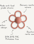 The mushie Daisy Rattle Teether is a pink, flower-shaped teether with textured loops, a solid center, soothing rattle sound, and an easy grip. Made from food-grade silicone and free from BPA, BPS, PVC, and phthalates.