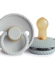 The Mushie FRIGG Rope Natural Rubber Pacifier 2-Pack features two gray pacifiers with a rope-textured edge—one stands upright showing the latex nipple, the other displays its ring handle. Perfect baby essentials.
