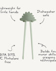 Mushie Training Chopsticks in pale green help toddlers learn self-feeding with labeled features.
