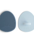 The mushie Cradle Cap Brushes in Tradewinds/Periwinkle include two silicone scrubbers—one with gentle bristles for cradle cap, the other with a smooth side and handle, perfect for baby bath time.