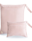 Two blush mushie Water Resistant Wet Bags, one large and one small, with wrist straps and bottom-left tags are shown on a white background—ideal for diaper bag storage.