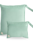 Two mushie Water Resistant Wet Bags in Roman Green, one large and one small, stand upright on a white background. Each features an attached wrist strap and a beige tag—ideal for diaper bag organization.