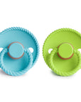 The Mushie FRIGG Rope Natural Rubber Pacifier 2-Pack features blue and green pacifiers with braided handles, circular shields, and embossed branding—perfect baby essentials.
