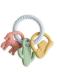 A mushie Western Teething Ring features a pink horse, green cactus, and yellow cowboy hat.
