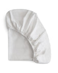 The mushie Stretchy MINI Crib Sheet, made from breathable organic cotton with elastic edges for a snug fit, is neatly folded and displayed on a plain white background.