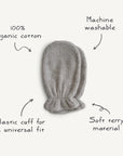 The Mushie Organic Cotton Bath Mitt in grey is made from soft terry, features elastic cuffs, a universal fit, and is machine washable—ideal for sensitive skin and gentle everyday use.