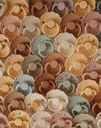 The FRIGG Daisy Natural Rubber Pacifier 2-Pack | Limited Edition features pastel-colored pacifiers in beige, brown, green, and peach with natural rubber latex nipples, arranged closely together in an overlapping display.