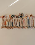 A set of FRIGG Natural Rubber Pacifier 4-Pack by FRIGG, each paired with a beaded silicone clip in assorted colors and animal shapes, is neatly arranged on a light beige surface.