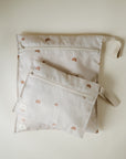 Two light beige mushie Water Resistant Wet Bags, one large and one small, each with a fabric loop and orange rainbow print. Ideal for diaper bag storage or organizing wet items. Shown on a plain light background.
