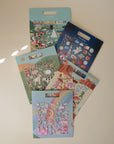 Collection of colorful sticker books on a light beige surface