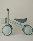 Mushie Mini Toddler Bike in mint green with front basket, shown on a beige background.