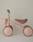 The mushie Mini Toddler Bike in beige and pink has a front basket—great as a first bike.