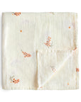 The mushie Organic Cotton Muslin Swaddle Blanket in Flowers color is neatly folded, showcasing its subtle quilted pattern and scattered orange floral prints on a plain white background, with one corner flipped to reveal the reverse side.