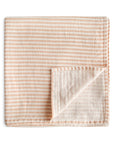 The mushie Organic Cotton Muslin Swaddle Blanket in Natural Stripe is shown folded on a white background, with one corner turned up to reveal the reverse side.