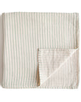 The mushie Organic Cotton Muslin Swaddle Blanket in Sage Stripe features lightweight, folded muslin with vertical green and beige stripes on white—soft and gentle for babies, perfect as a cozy organic cotton blanket.