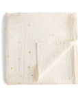 The mushie Organic Cotton Muslin Swaddle Blanket in Sun is cream-colored with a subtle yellow sun pattern, neatly folded with one corner turned up. Made from organic cotton for softness and comfort.