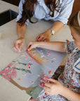 Two people working on a craft project with floral designs on a table.