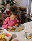 A girl packs snacks in mushie Silicone Baby Food Containers at a festive cookie decorating table.