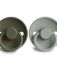 The Mushie FRIGG Rope Natural Rubber Pacifier 2-Pack features two round pacifiers—one olive green and one light gray—with rope-like handles, natural rubber latex nipples, and FRIGG embossed on each, displayed side by side on a white background.