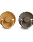 The Mushie FRIGG Rope Natural Rubber Pacifier 2-Pack features round pacifiers with rope-textured edges and handles in mustard yellow and taupe gray, both with natural rubber latex nipples—essential baby items shown side by side on a white background.