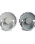 The Mushie FRIGG Rope Natural Rubber Pacifier 2-Pack features two round pacifiers with rope-textured edges and circular handles in light and dark gray, laid side by side on a white background—essential for babies.