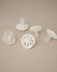 Five FRIGG Andersen Fairytale Silicone Pacifier 2-Packs, all white with scalloped edges, are arranged on a beige surface; each FRIGG pacifier is expertly crafted in Denmark with quality and charming design.