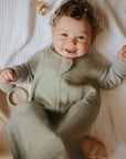 Lifestyle picture of a Mushie Sleep Bag in Sage on a baby.